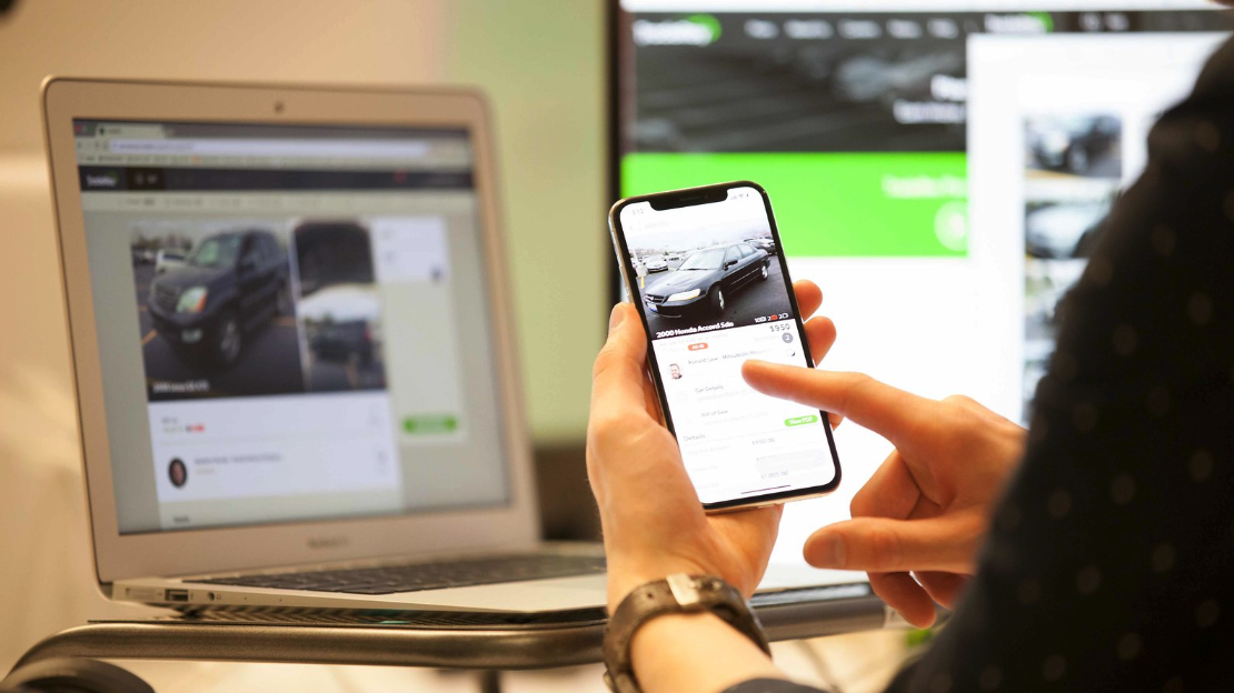 Person using smartphone to participate in an online auto auction