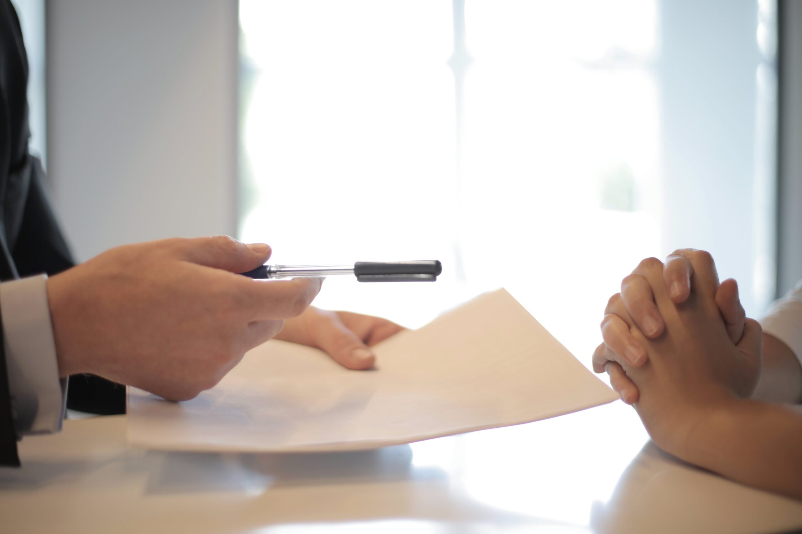 An auto bank floor plan financing lender hands a loan agreement and pen to a nervous and unsure auto dealer still deciding on who to use for their floorplan financing.