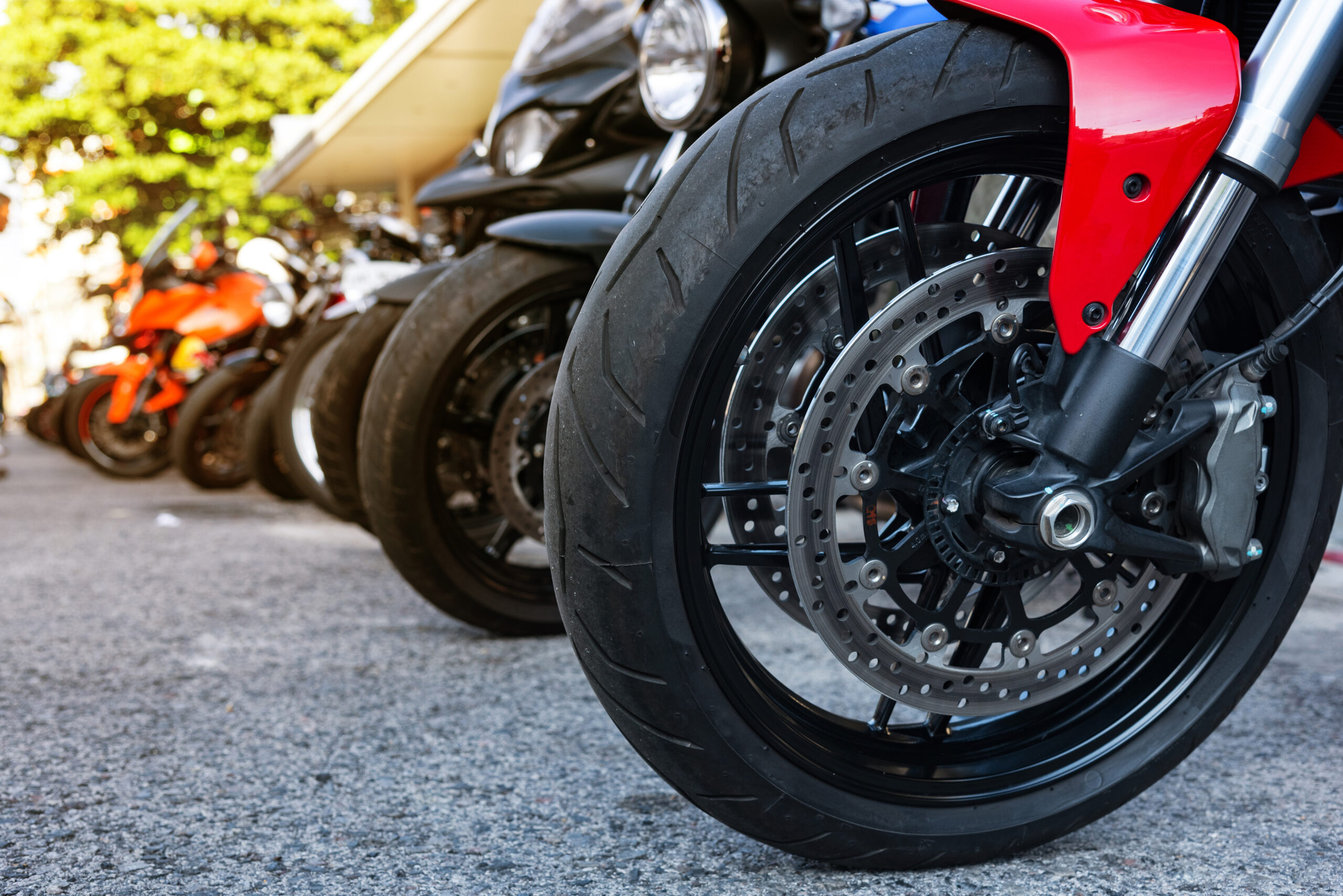 Line of motorcycle front wheels with red mud guard.