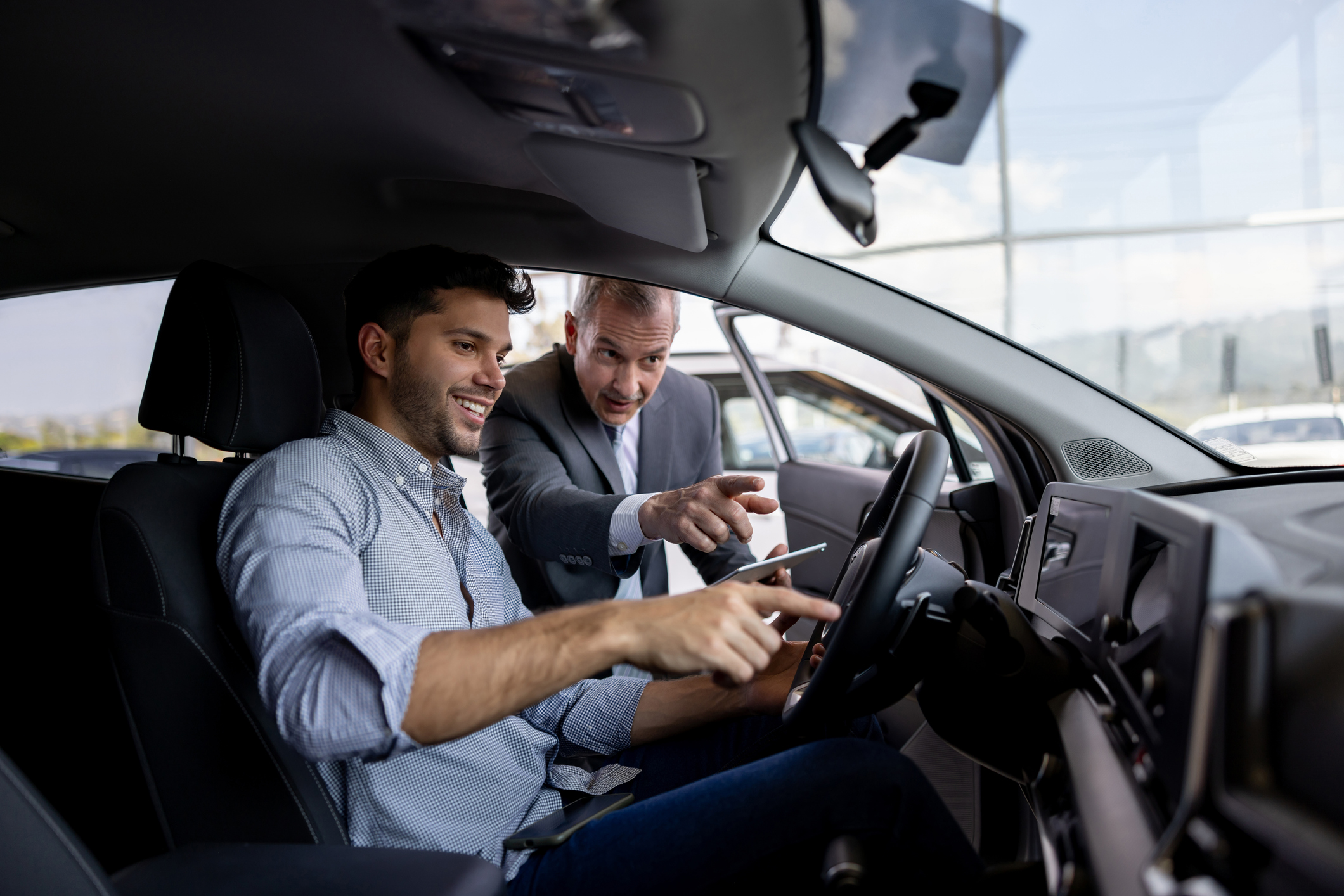 Car Dealer and customer look at interior of car.