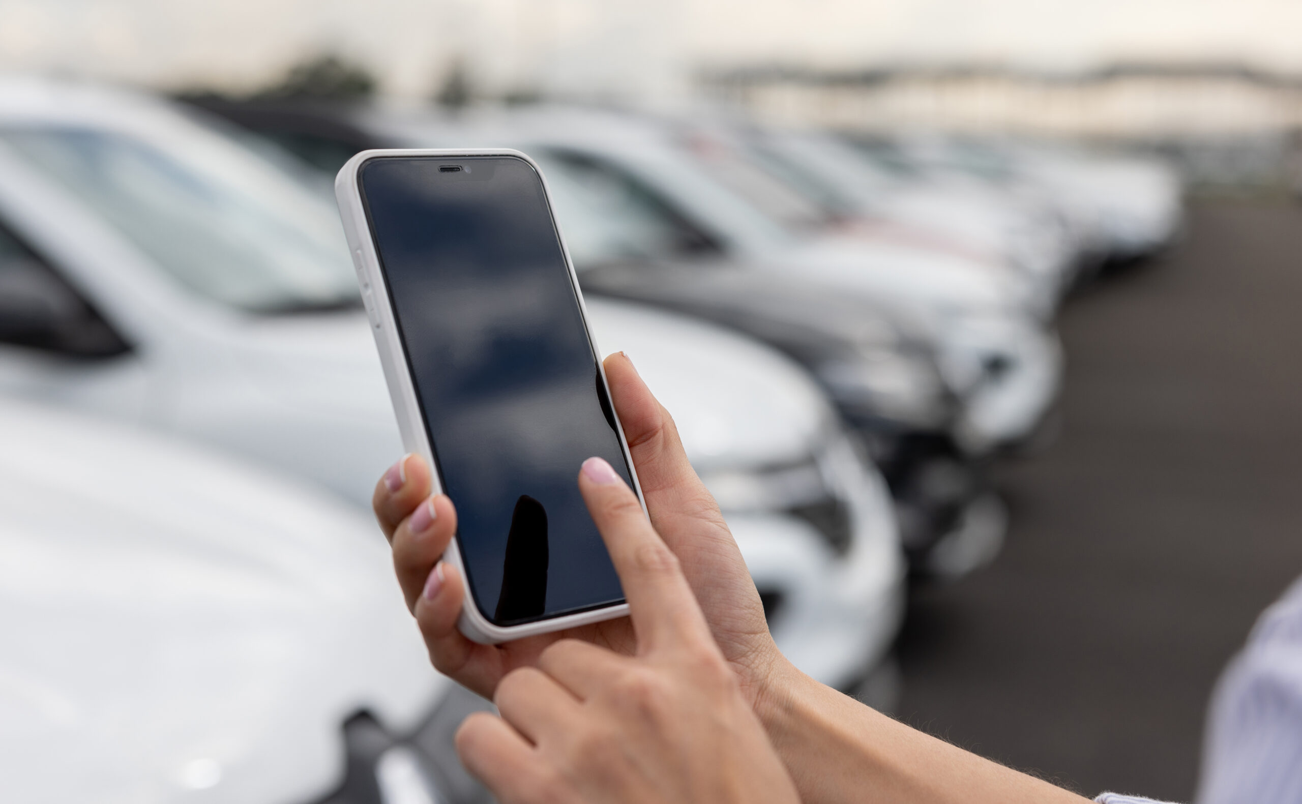 Close-up on a person using a mobile app on their smartphone at a car dealership