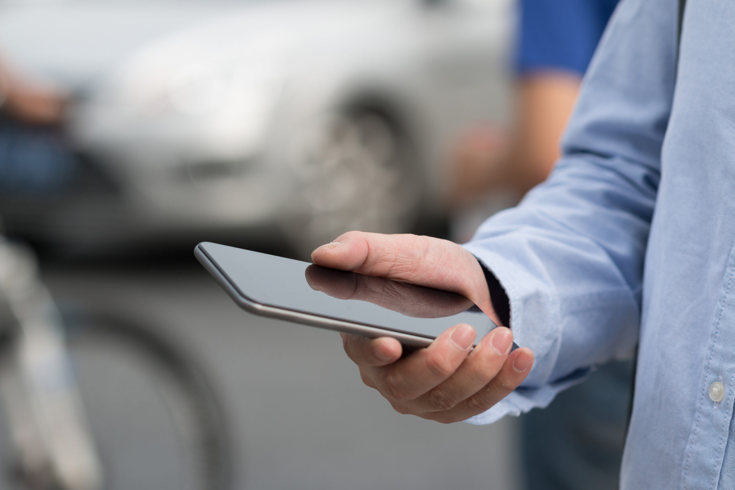 person using phone on the street with car in the background
