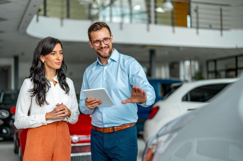 Car salesmen showing woman a car.