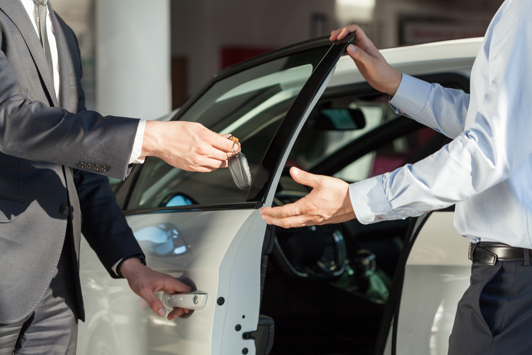 Car Salesman's hands giving key to male customer.